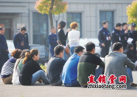 7 名传销人员被控制后坐在地上。